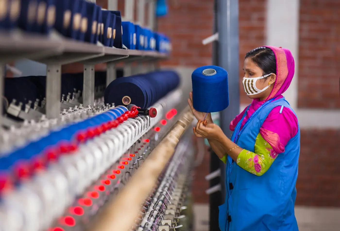 A worker checking yarn on a spinning machine