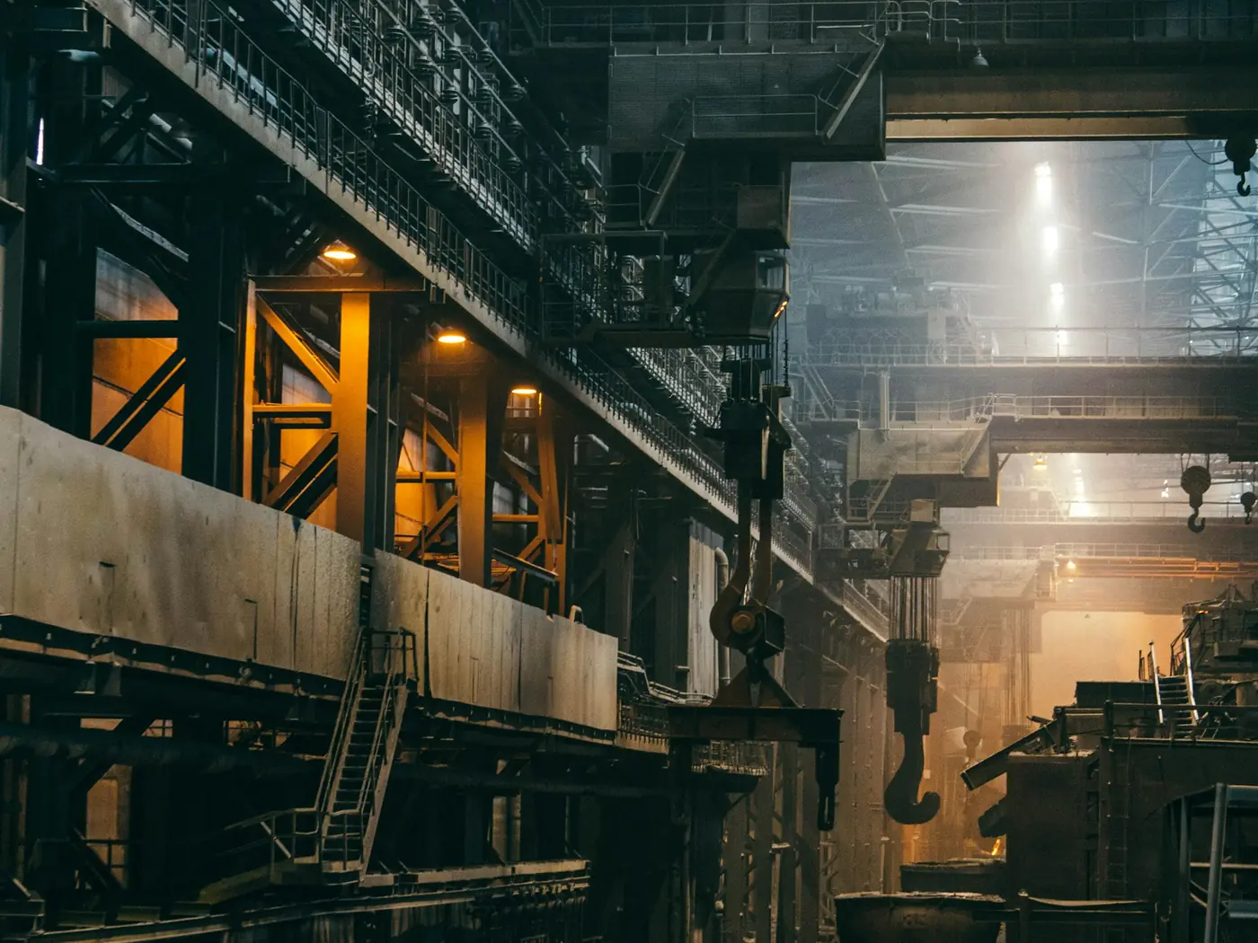 Inside a steel plant, cranes and furnaces under a high roof